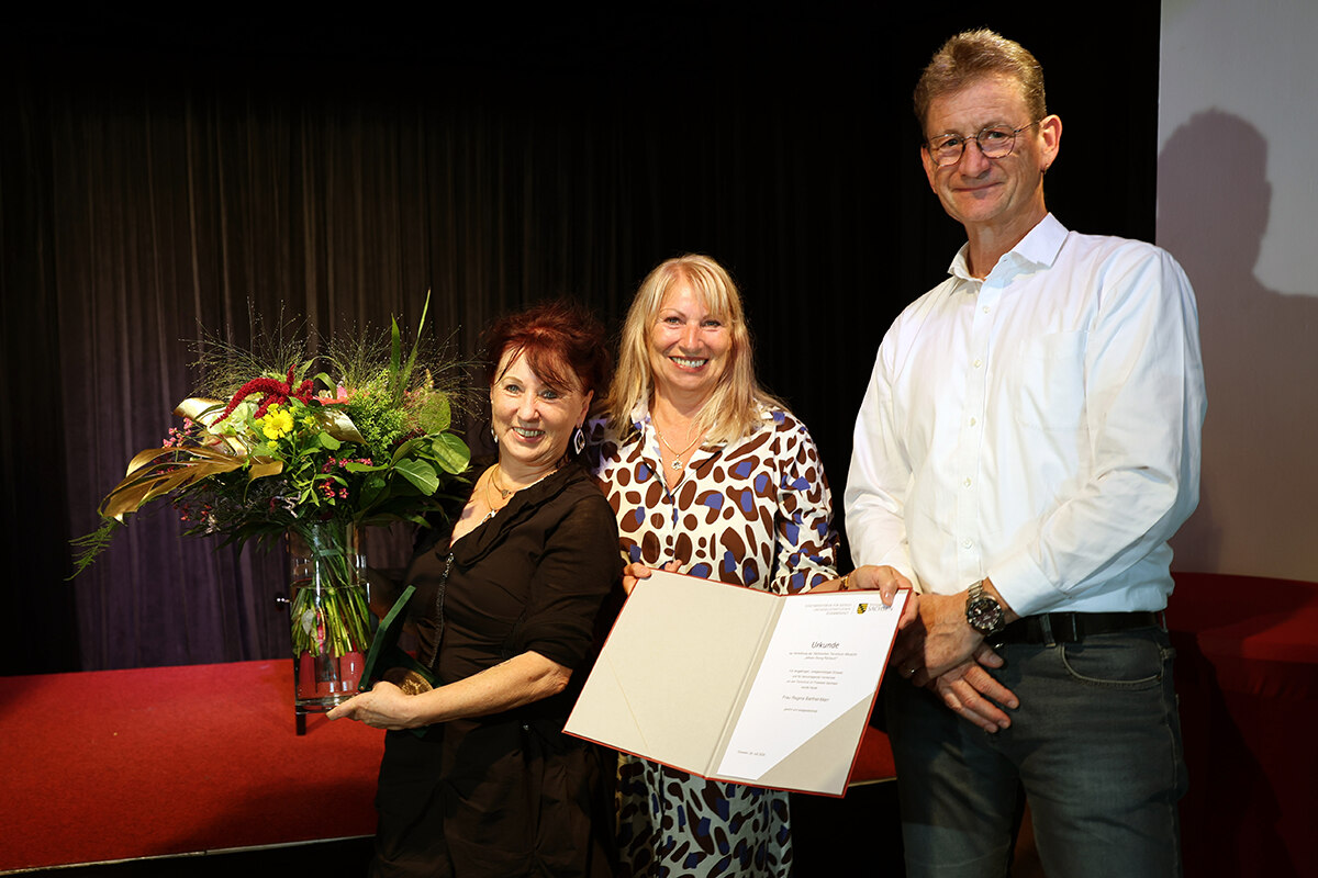 Verleihung der Tierschutzmedaille: Regina Barthel-Marr, Petra Köpping und Dr. Stephan Koch stehen glücklich nebeneinander. Frau Barthel-Marr hält Blumen in der Hand, Petra Köpping die Gewinnerurkunde.